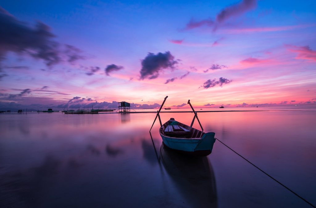 white and blue boat on water under blue sky during daytime